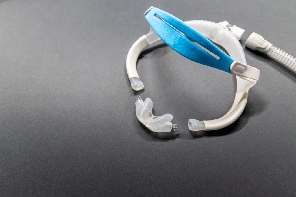 Moderne CPAP-Nasenmaske auf grauem Hintergrund, bereit für die Schlafapnoe-Therapie.