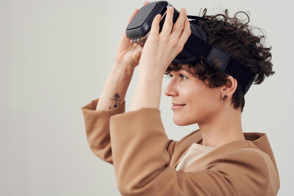 Lächelnde Frau setzt eine VR-Brille ab, umgeben von natürlichem Licht. Die Szene zeigt den entspannten Umgang mit innovativer Schlaftherapie-Technologie.