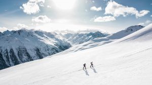 Zwei Personen, die in einer verschneiten Berglandschaft Skiwandern – illustriert die Vorteile von Outdoor-Sportarten in der Schweiz für körperliche Fitness und besseren Schlaf.
