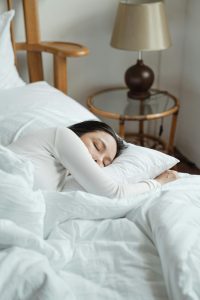 Eine Frau schläft friedlich in einem gemütlichen Bett, nachdem sie Yoga am Abend praktiziert hat. Das Bild symbolisiert den positiven Einfluss von Yoga auf die Schlafqualität.